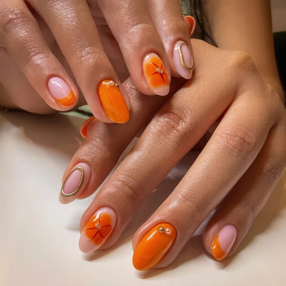 Orange flower nail art with gold accents on almond nails
