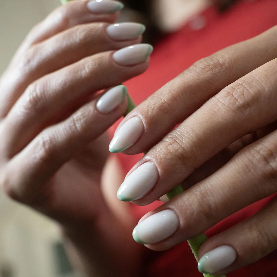 Sage green outlined French tips on milky almond nails